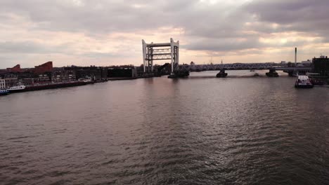 Aufsteigender-Dolly-Aus-Der-Luft-über-Oude-Maas-Mit-Blick-Auf-Die-Erhöhte-Eisenbahnbrücke-Spoorbrug-Vor-Dem-Sonnenuntergangshimmel-In-Dordrecht