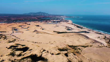 Drone-shot-of-large-sand-dunes-field-and-shoreline-with-Pacific-Coastline-during-summer-in-Vietnam