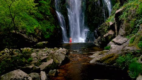 Macho-Adulto-Con-Pantalones-Cortos-Rojos-Vadeando-El-Agua-En-La-Base-De-Las-Cascadas-De-Fervenza-Do-Toxa