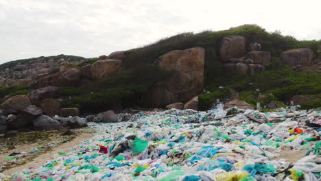 Drone-pullback,-dirty-beach-shore-filled-with-plastic-ocean-trash-pollution