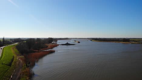 Aerial-Rising-From-Beside-Der-Lek-Forward-Dolly-Towards-Sendo-Liner-Inland-Freighter-Passing-Through-Groot-Ammers