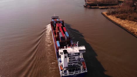 Aerial-Over-Stern-Of-WEC-de-Hoogh-Cargo-Ship-Navigating-Along-Oude-Maas