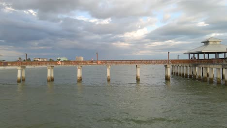 Tourist-visitors-walking-on-Fort-Myers-beach-Pier,-aerial-view,-Florida