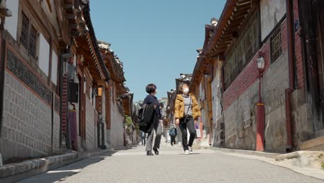 Mujeres-Coreanas-Mayores-Con-Máscaras-Viajan-En-La-Aldea-De-Bukchon-Hanok-En-Seúl,-Corea-Del-Sur