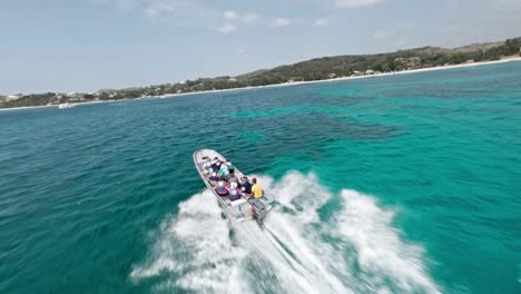 Akrobatische-Drohne-Fliegt-über-Ein-Touristenboot,-Das-Im-Blauen-Meer-Am-Strand-Von-Playa-Ensenada-In-Der-Dominikanischen-Republik-Navigiert