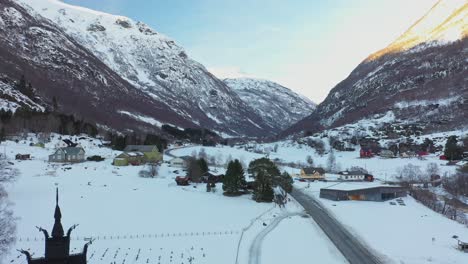 Borgund-valley-close-to-Laerdal-Norway---Upward-moving-aerial-close-to-stave-churc-revealing-panoramic-view-during-winter-sunset