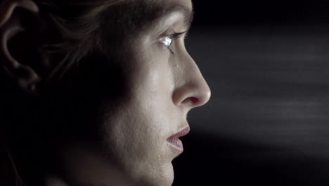 Side-profile-of-a-female-face-staring-into-a-light-shaft-in-a-studio-with-black-background