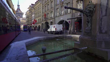 Bern,-historic-fountain-on-Marktgasse-street-with-eco-friendly-public-transport