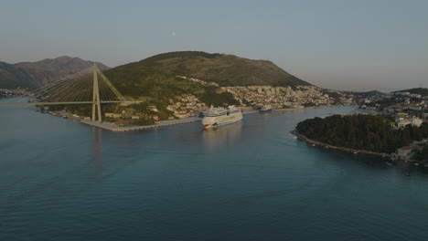 Crucero-Aidnova-En-El-Puerto-De-Dubrovnik,-Croacia,-Con-Vistas-A-La-Ciudad-Costera,-Drone-Aéreo-De-5k