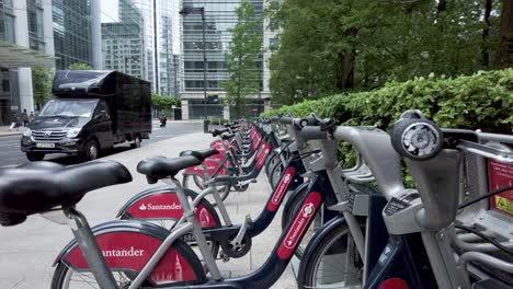 A-close-up-shot-of-a-row-of-Santander-bicycles-docked-along-Upper-Bank-Street,-the-bicycles-are-a-rent-to-hire-scheme-and-also-known-as-Boris-Bikes,-London,-England