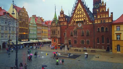 European-downtown-city-square-old-town,-rainy-day-and-people-with-umbrellas,-Time-lapse