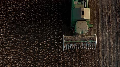 Birds-eye-aerial-view-of-John-Deere-tractor-in-Bulgarian-sunflower-field-harvesting-seeds-summers-evening