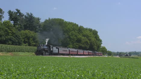 A-1924-Steam-Engine-with-Passenger-Train-Puffing-Smoke-Traveling-Along-the-Amish-Countryside-on-a-Summer-Day