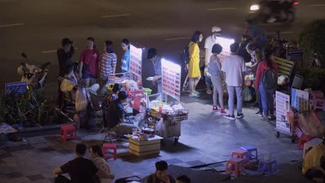 Jóvenes-Comiendo-Comida-Callejera-Por-La-Noche-En-Vietnam.