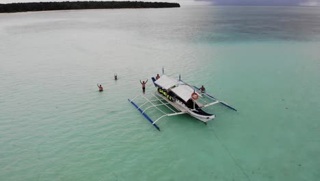 Toma-Aérea-En-órbita-De-4k-De-Personas-Saludando-En-Un-Pontón-Banca-Anclado-En-Aguas-Tranquilas-Del-Océano-De-Balabac-Palawan-En-Filipinas