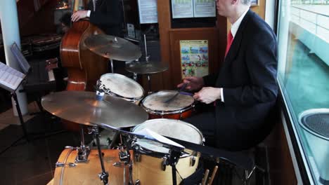 Baterista-Caucásico-Tocando-La-Batería-Mientras-Llevaba-Traje-Y-Corbata-En-Un-Barco