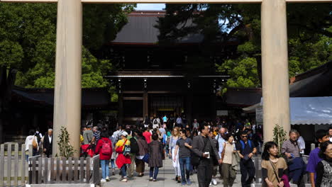 Cámara-Lenta-De-Una-Gran-Multitud-Caminando-Bajo-Un-Gran-Santuario-Torii-Y-Meiji-Jingu