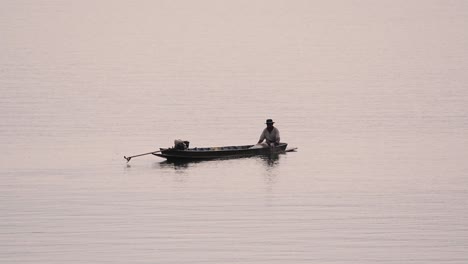 Fisherman-silhouetting-as-he-is-casting-and-drawing-his-net-in-the-River-before-dark,-in-slow-motion