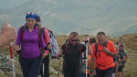 Un-Gran-Grupo-De-Personas-Con-Bastones-De-Trekking-Suben-Hasta-La-Cima-De-Pietrosu-Rodnei,-Rumania