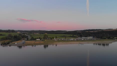 Ein-Professionell-Aussehender-Luftflieger,-Der-Bei-Warmem-Sonnenuntergang-Auf-Einen-Deutschen-Campingplatz-Am-Ruhigen-Spiegelsee-Zufliegt