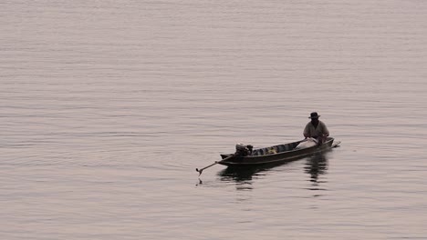 Pescador-Perfilando-Mientras-Lanza-Y-Saca-Su-Red-En-El-Río-Antes-Del-Anochecer,-En-Cámara-Lenta