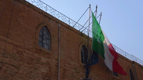 Italian-National-Flag-Waving-On-The-Facade-Of-Building-In-Syracuse,-Sicily