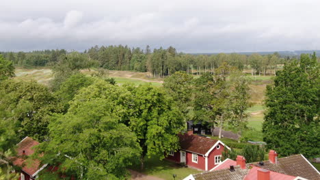 Luftaufnahme-In-Richtung-Eines-Hügeligen-Golfplatzes-In-Schweden,-Umgeben-Von-Bäumen