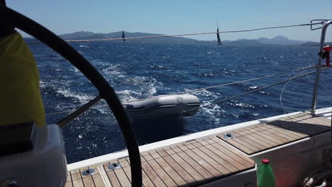 Dinghy-on-the-back-of-a-sailboat-gets-hit-by-the-waves-of-the-mediterranean-sea,-Sardinia,-Italy