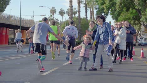 Adorable-Niño-Chocando-Los-Cinco-Con-Los-Corredores-De-Maratón-En-Málaga,-España,-Multitud-Animando-A-Los-Deportistas.