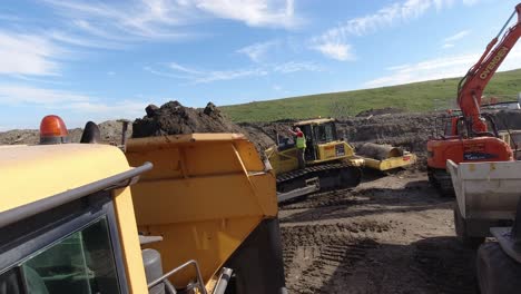 Captura-De-Cámara-De-Acción-De-Un-Camión-Volquete-Dando-Marcha-Atrás-Y-Volcando-Tierra-En-Un-Gran-Sitio-De-Construcción