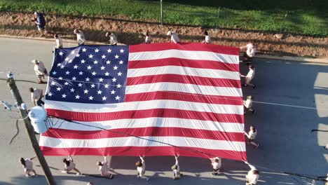 Aerial-tilt-down-and-pan-as-Boy-Scouts-carry-American-flag-in-parade-in-United-States-of-America,-Pennsylvania