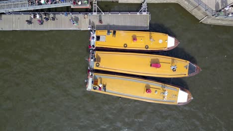 Vista-Aérea-De-Arriba-Hacia-Abajo-De-Personas-Bajando-De-Tres-Barcos-Atracados-Uno-Al-Lado-Del-Otro