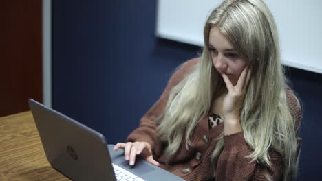 Aufnahme-Einer-Blonden-Frau,-Die-An-Einem-Tisch-Sitzt-Und-An-Ihrem-HP-Laptop-Arbeitet