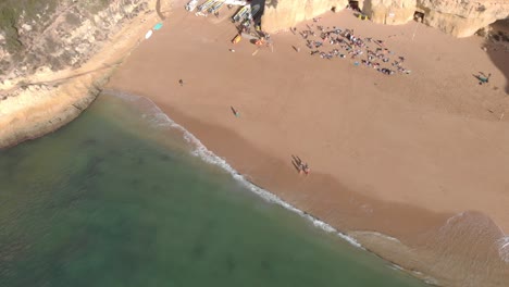 Tourists-enjoying-a-beautiful-day-in-the-beach-of-Benagil,-Portugal-on-a-bright-sunny-day---Aerial-shot