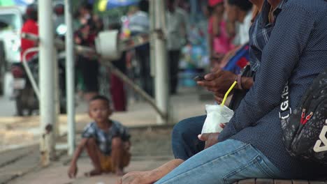 Niño-En-Cuclillas-En-El-Fondo-Mientras-Los-Hombres-Se-Sientan-En-Un-Banco-En-Primer-Plano