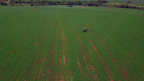 Tractor-spraying-large-soybean-plantation,-aerial-footage