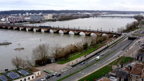 Toma-Panorámica-De-La-Ciudad-Que-Muestra-El-Pont-De-Pierre,-El-Río-Garona,-La-Basílica-De-San-Miguel-Y-La-Puerta-De-La-Ciudad-Mientras-Nieva-Ligeramente,-La-Panorámica-Aérea-A-La-Derecha-Revela-Una-Toma-Suspendida