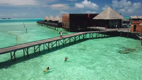 Aerial,-drone-shot,-around-people-playing-in-the-water,-at-villas-on-the-sea,-on-a-sunny-day,-on-the-Conrad-Rangali-island,-in-Maldives
