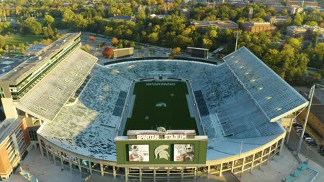 Aerial,-empty-football-stadium,-Michigan-State-University,-pedestal-up-tilt-down