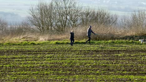 Pair-walking-dog-recreational-activity-British-countryside-farmland-hill