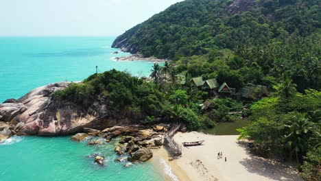Beautiful-hidden-beach-with-white-sand,-big-cliffs-crushed-by-sea-waves-on-tropical-island-with-green-trees-in-Thailand
