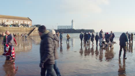 Winterlich-Gekleidete-Meeresschwimmer-Und-Zuschauer-Versammeln-Sich-Am-Strand-Von-Scarborough,-Großbritannien,-Zum-Alljährlichen-Neujahrsschwimmen-Im-Meer