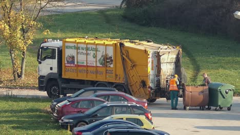 Müllcontainer-Mann-LKW-Mit-Zwei-Arbeitern,-Die-Die-Vollen-Mülltonnen-Leeren