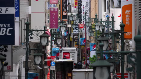 Cámara-Lenta-De-Una-Calle-Estrecha-De-Tokio-Llena-De-Carteles-Publicitarios-Y-Farolas