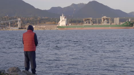 Un-Hombre-Vestido-Con-Un-Chaleco-Rojo-De-Invierno-Y-Una-Sudadera-Con-Capucha-Fue-A-Pescar-En-Un-Lago-En-Vancouver-Una-Tarde:-Plano-Amplio