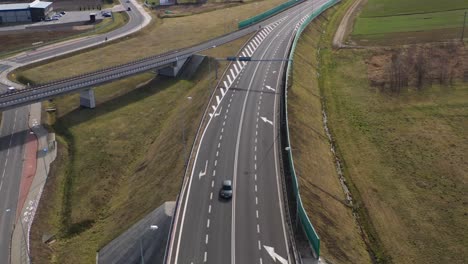 Aerial-wide-angle-fly-by-shot-of-the-traffic-on-a-highway-on-a-bright-sunny-afternoon