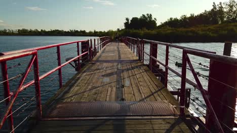 A-jogger-running-across-a-red,-wooden-floating-bridge