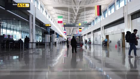 Slow-motion-view-of-passengers-walking-in-an-airline-terminal-and-waiting-for-flights-at-gates-in-nearly-empty-conditions