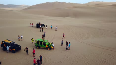 Aéreo,-Reverso,-Disparo-Con-Drones,-Lejos-De-Un-Grupo-De-Personas-Y-Buggies-4x4,-Sobre-Dunas-De-Arena,-En-El-Desierto-De-Atacama,-En-Un-Día-Soleado,-En-El-Sur-De-Perú