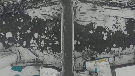 Aerial-Top-Down-Zoom-Out-shot-of-a-bridge-near-Old-Manali-covered-with-white-snowflakes-during-a-heavy-snowfall-in-the-winters,-shot-with-a-drone-in-4k